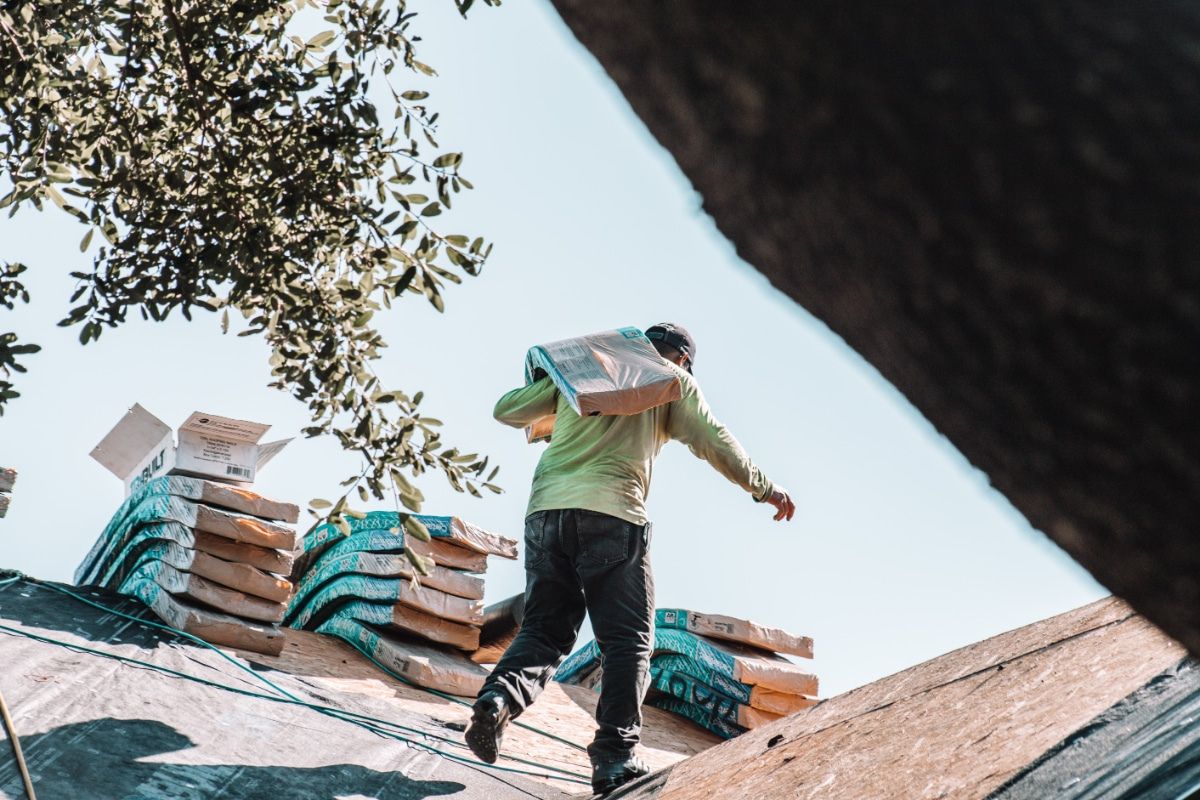 new construction roofing professional carrying shingles